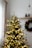Festive living room scene with a beautifully decorated artificial Christmas tree and warm string lights glowing softly.