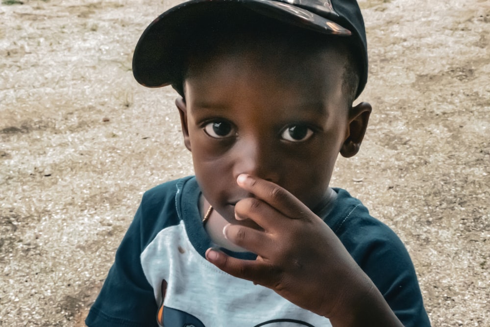 a young boy in a baseball cap eating something