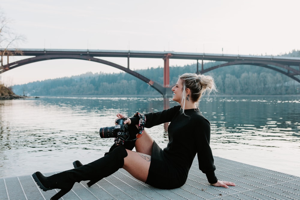 a woman sitting on a dock with a camera