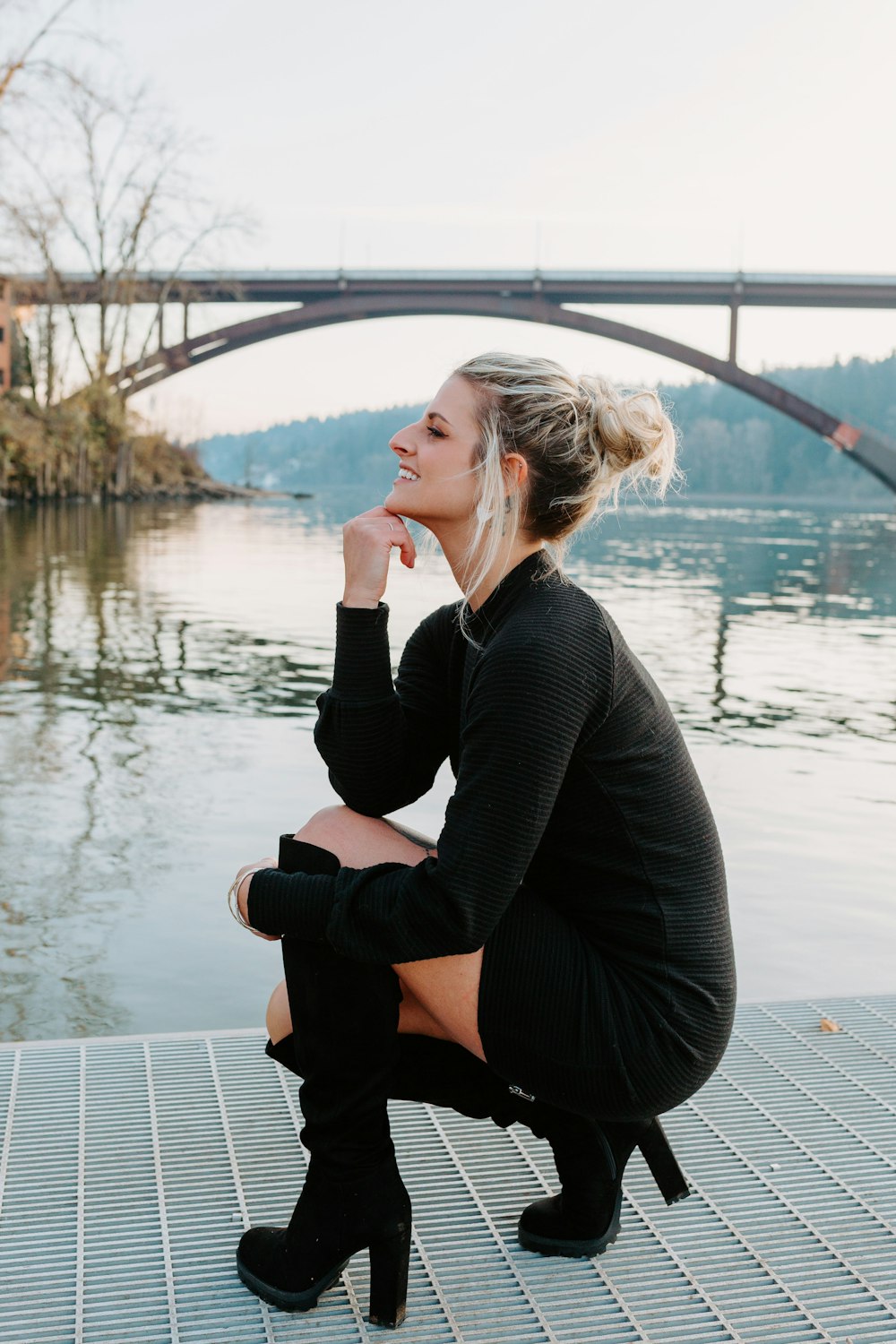a woman sitting on a dock next to a river