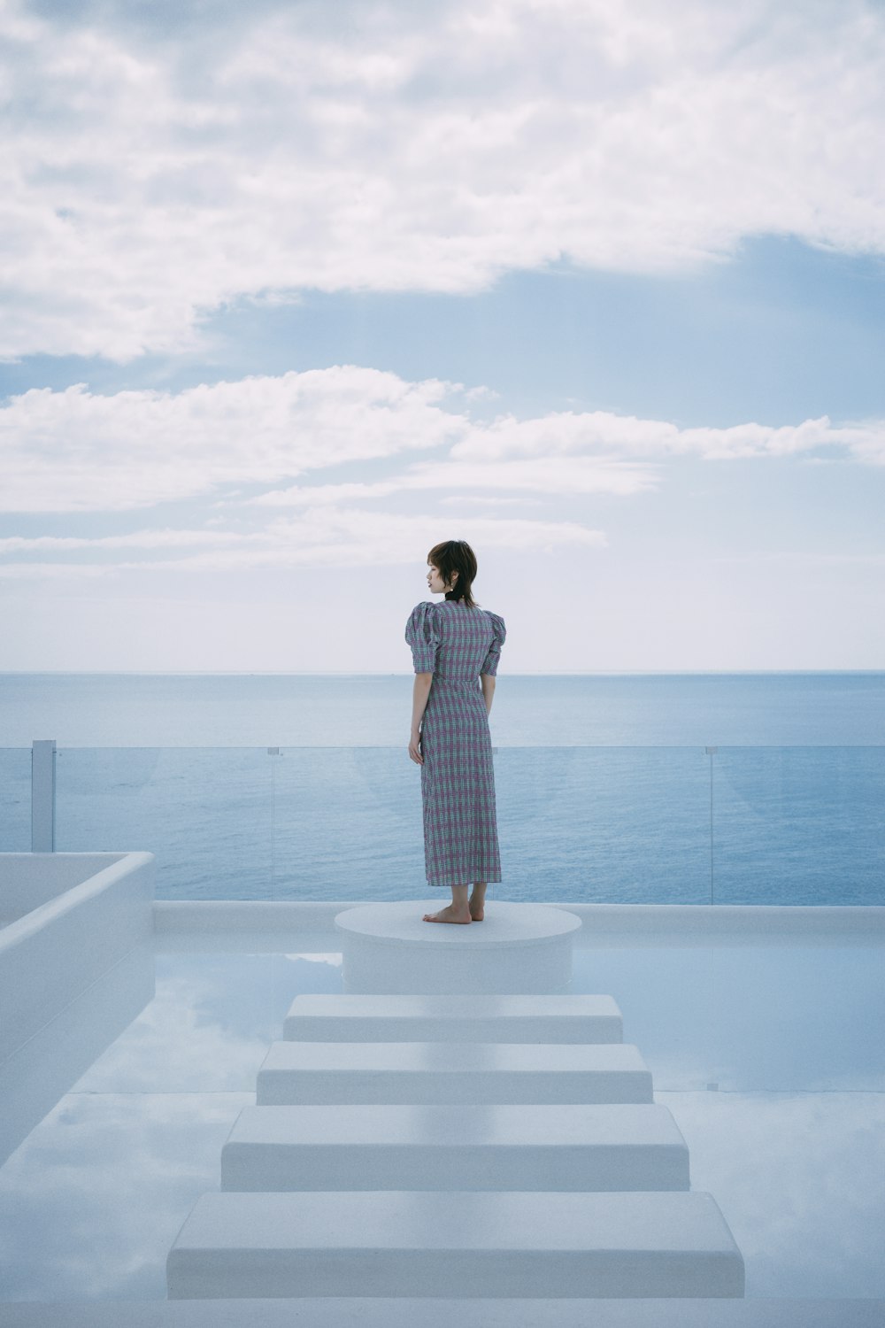 a woman standing on a set of stairs overlooking the ocean