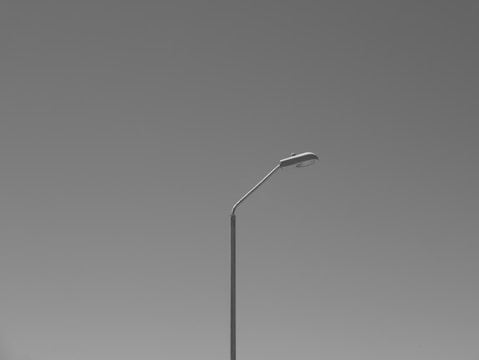 A minimalist shot of a lone streetlamp glowing against a dark city backdrop.