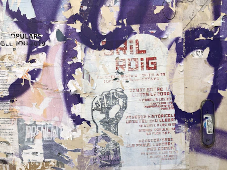 A weathered urban wall layered with peeling posters and graffiti, capturing the raw textures of forgotten city spaces.