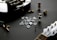 A collection of guitar picks is laid out on a dark surface, accompanied by various guitar components and accessories, including guitar strings, a tube amplifier, and a guitar headstock. The setup conveys a sense of musical creation and technical assembly.