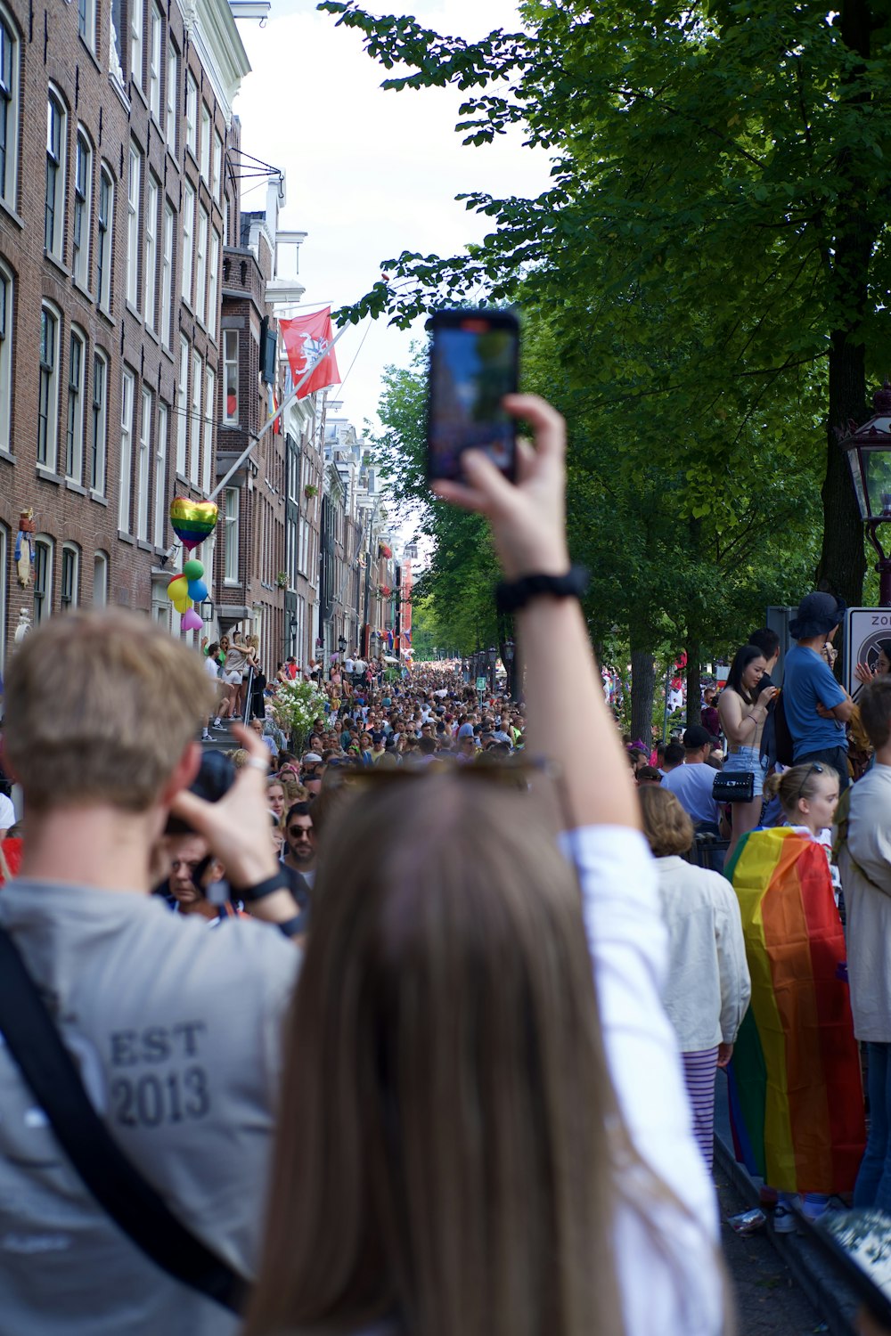 a crowd of people walking down a street next to tall buildings