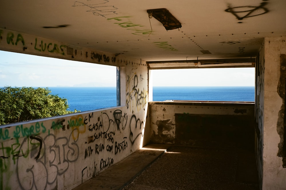 a room with graffiti on the walls and a view of the ocean