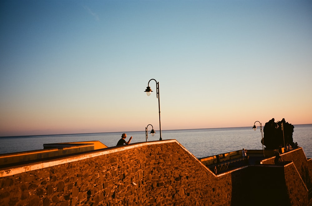 a person sitting on a wall near the ocean