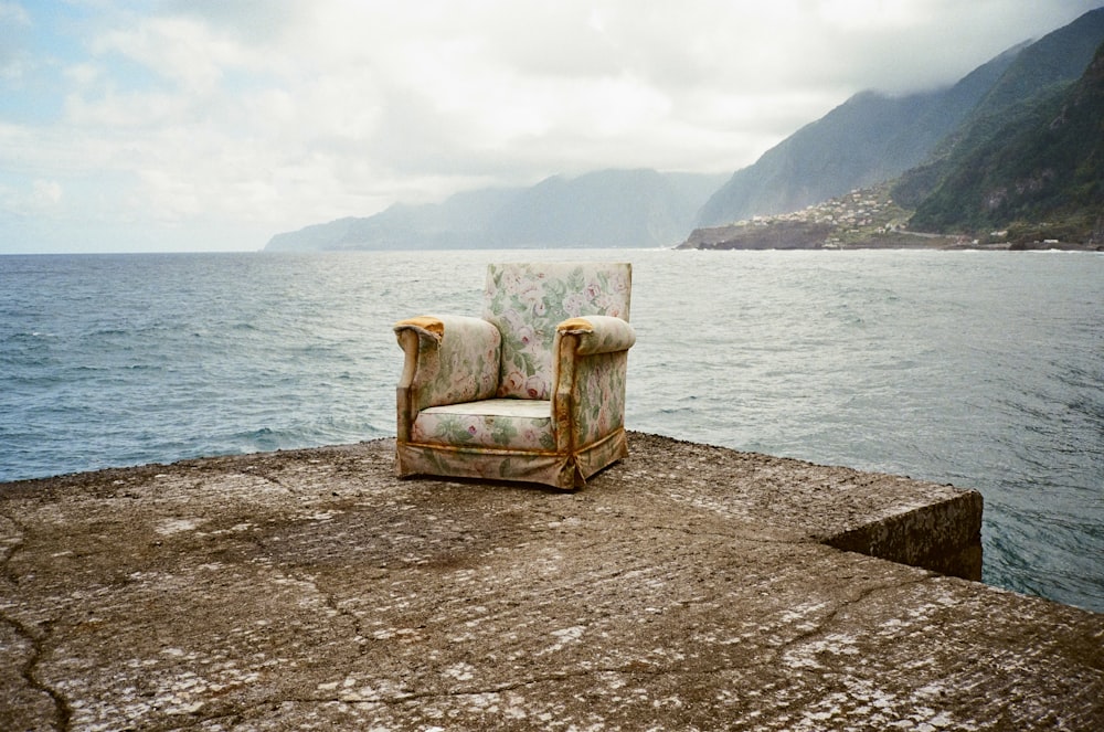 an old chair sitting on the edge of a pier