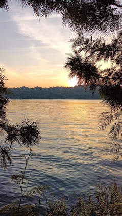 A serene sunset over a quiet lake, with soft musical notes floating gently in the air.