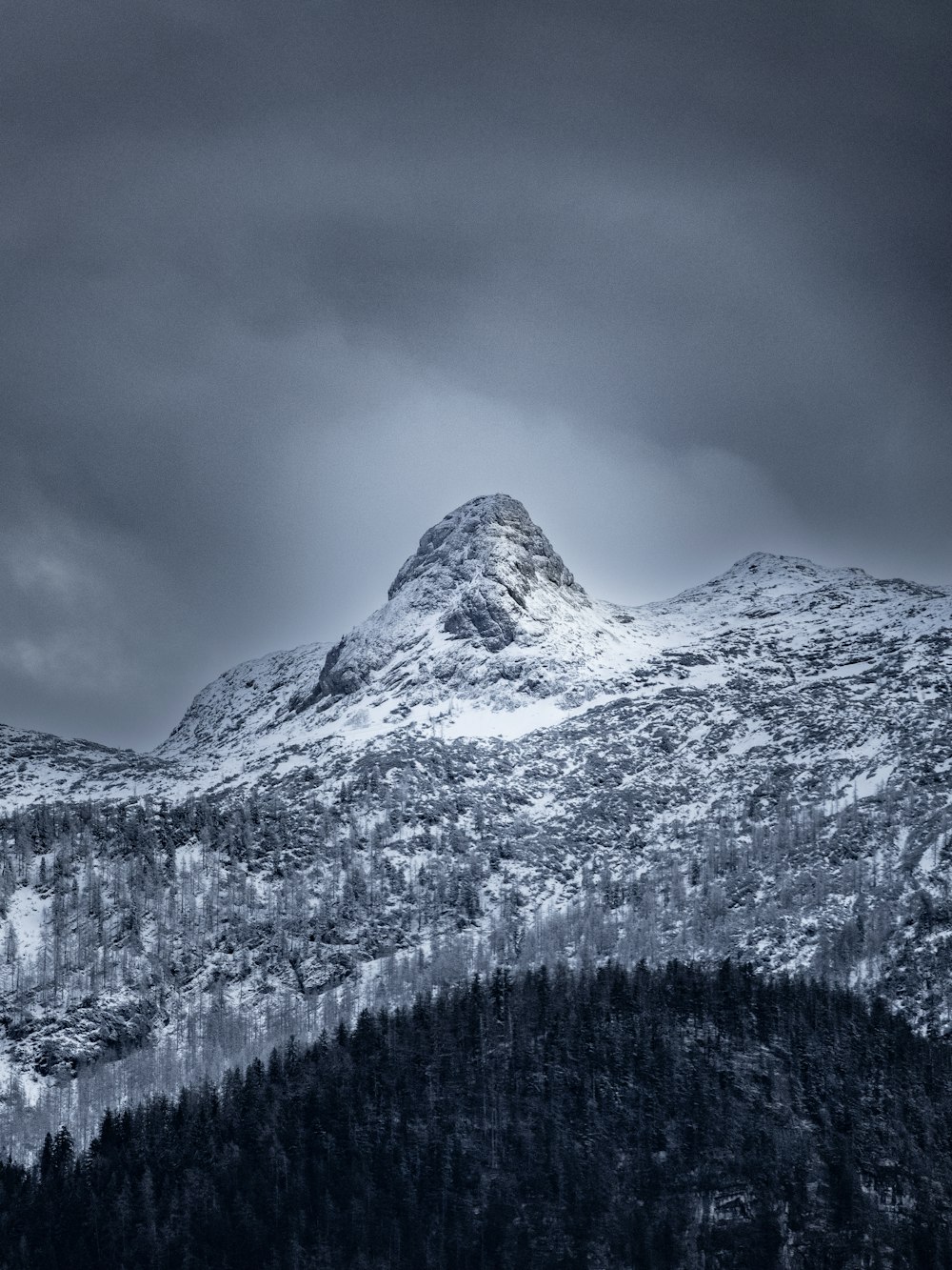 a mountain covered in snow under a cloudy sky