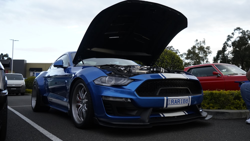 a blue car with its hood open in a parking lot