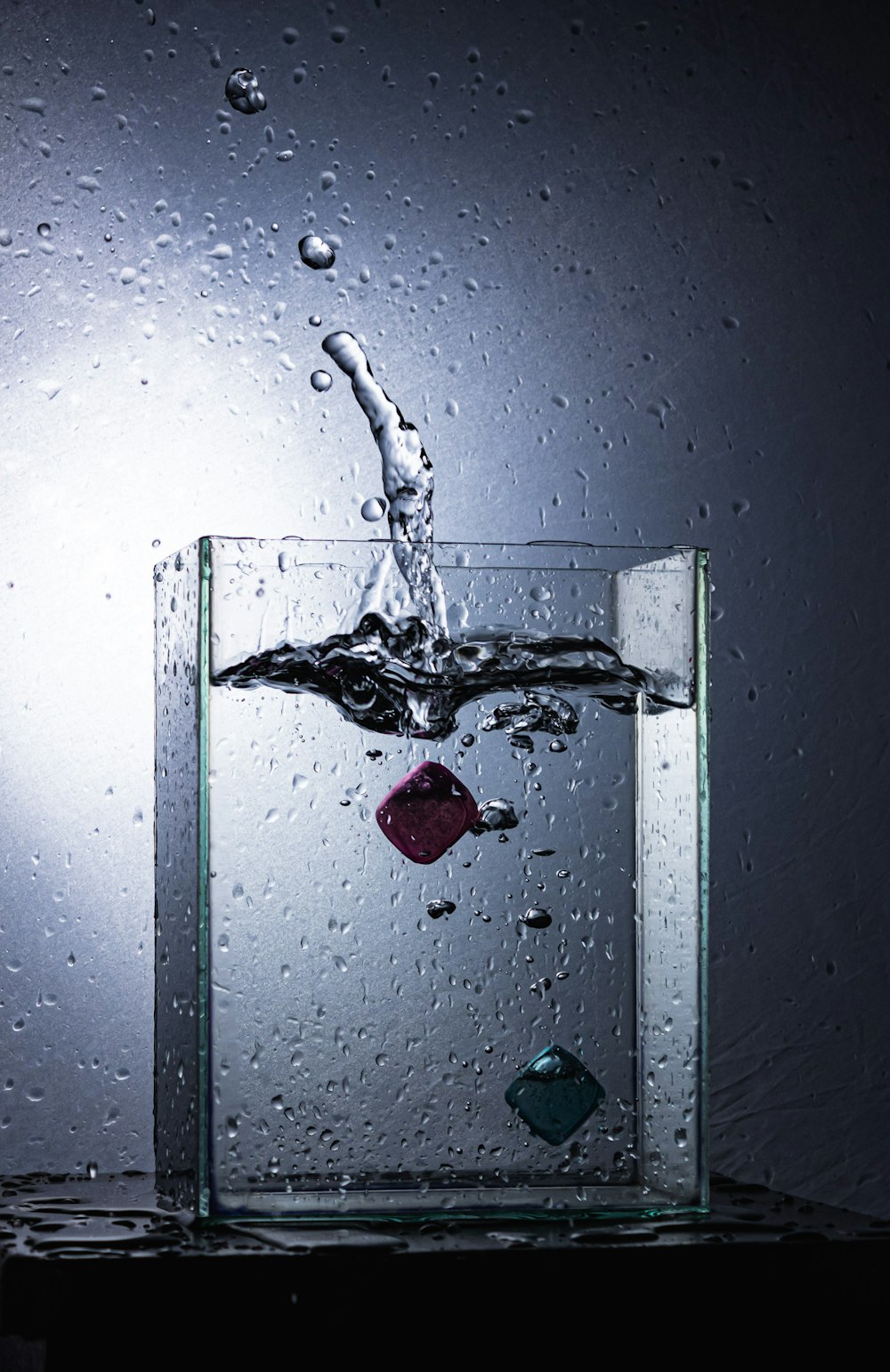 a glass of water with a drop of water coming out of it