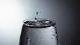 Close-up of a water droplet splashing into a clear glass, symbolizing purity and refreshment.