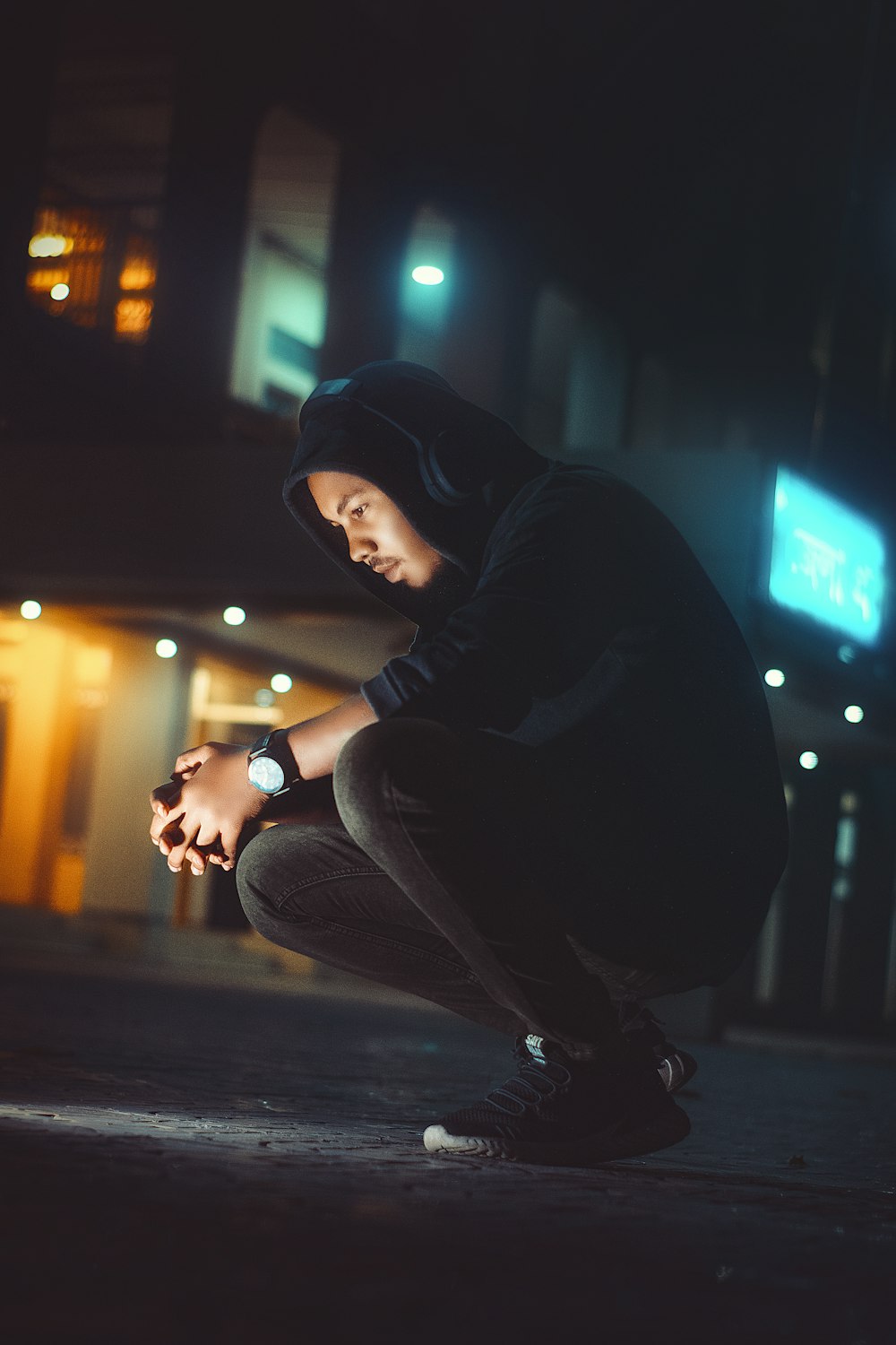 a young man crouching down while looking at his cell phone