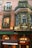 A storefront decorated with festive garlands and lights. The building features brick architecture and large windows. Greenery and red ornaments adorn the facade, while warm light emanates from inside, creating a cozy atmosphere. A canopy displays the name 'VITAVIEN' in white letters.