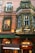 A storefront decorated with festive garlands and lights. The building features brick architecture and large windows. Greenery and red ornaments adorn the facade, while warm light emanates from inside, creating a cozy atmosphere. A canopy displays the name 'VITAVIEN' in white letters.