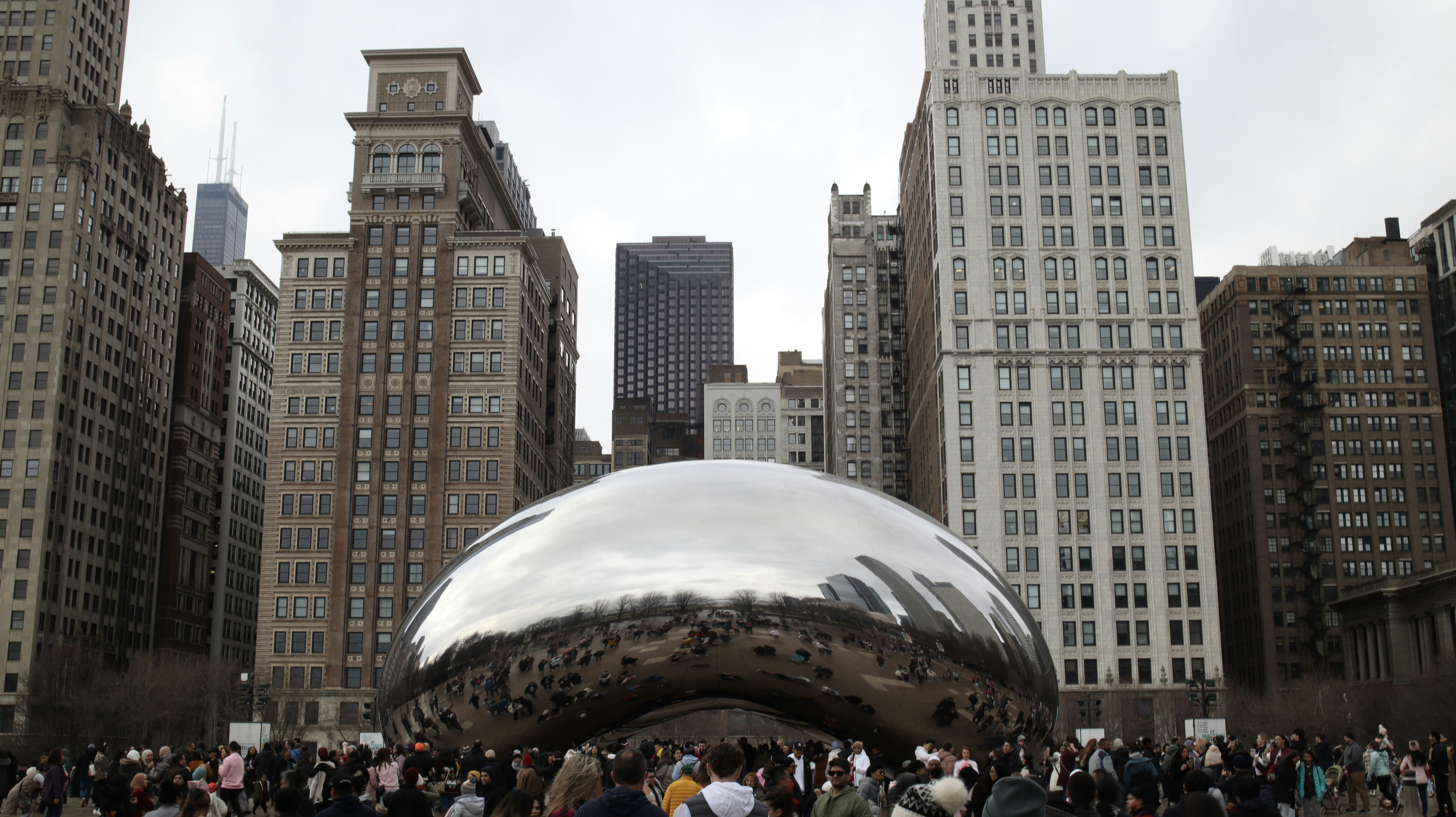 A group of people standing in front of a large metal ball