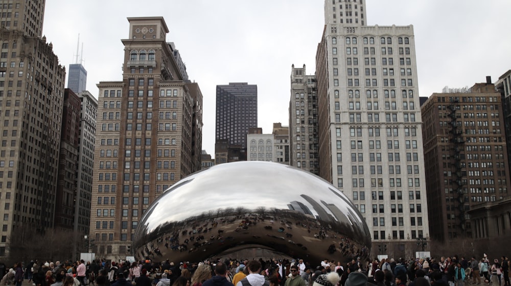 a group of people standing in front of a large metal ball