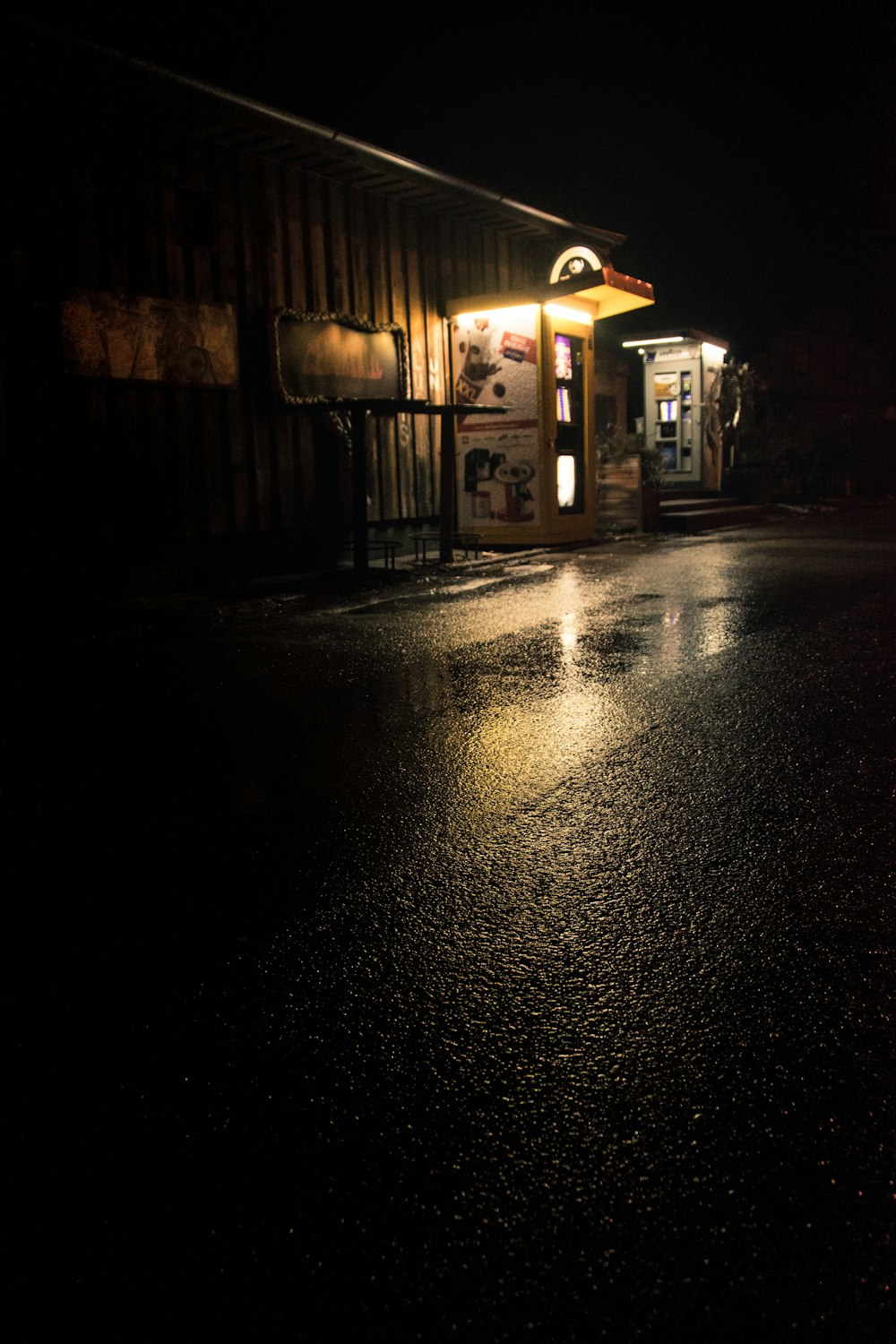 a dark street at night with a store front lit up