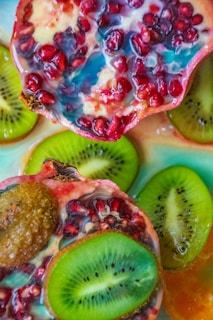 A vibrant fruit bowl filled with sliced kiwi, mango, and pomegranate seeds, styled with soft natural light