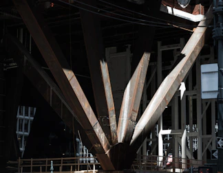 Close-up of hands measuring and cutting steel beams for structural support.