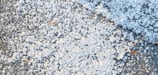 Close-up of bc icemelt granules scattered on a snowy driveway.