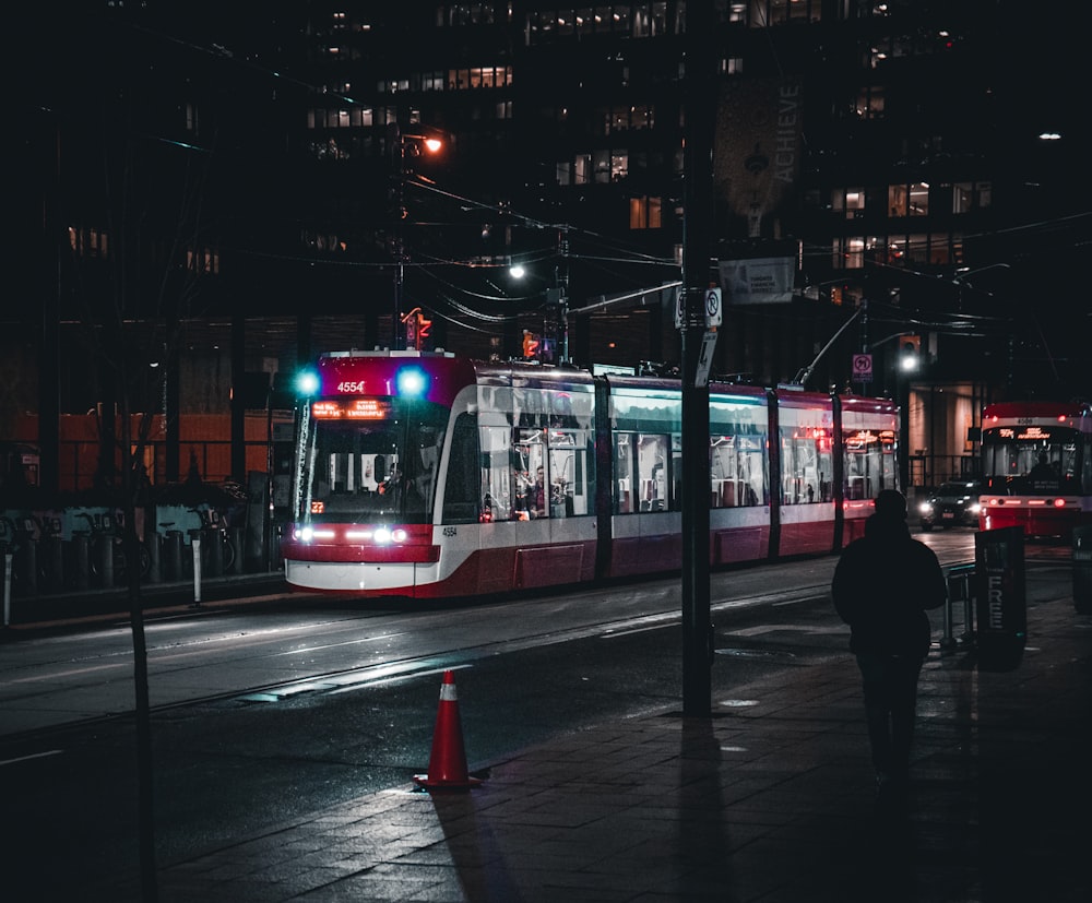 a red and white train traveling down train tracks at night