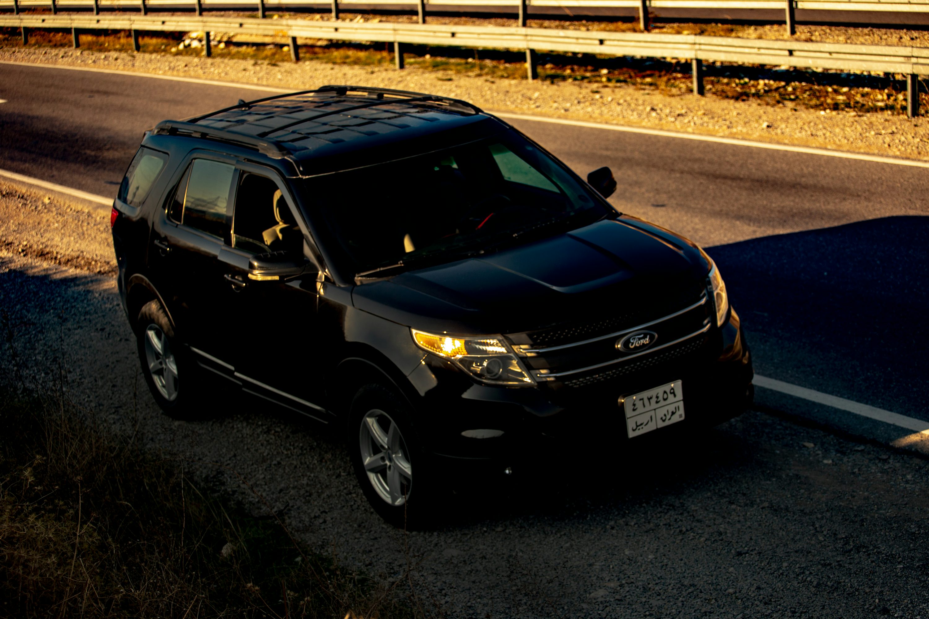 a black suv is driving down the road