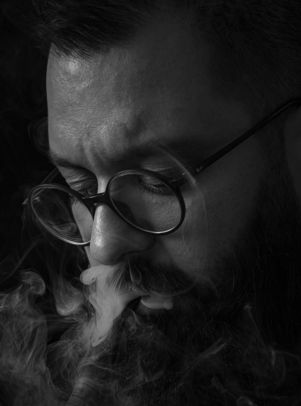 a man with glasses smoking a cigarette