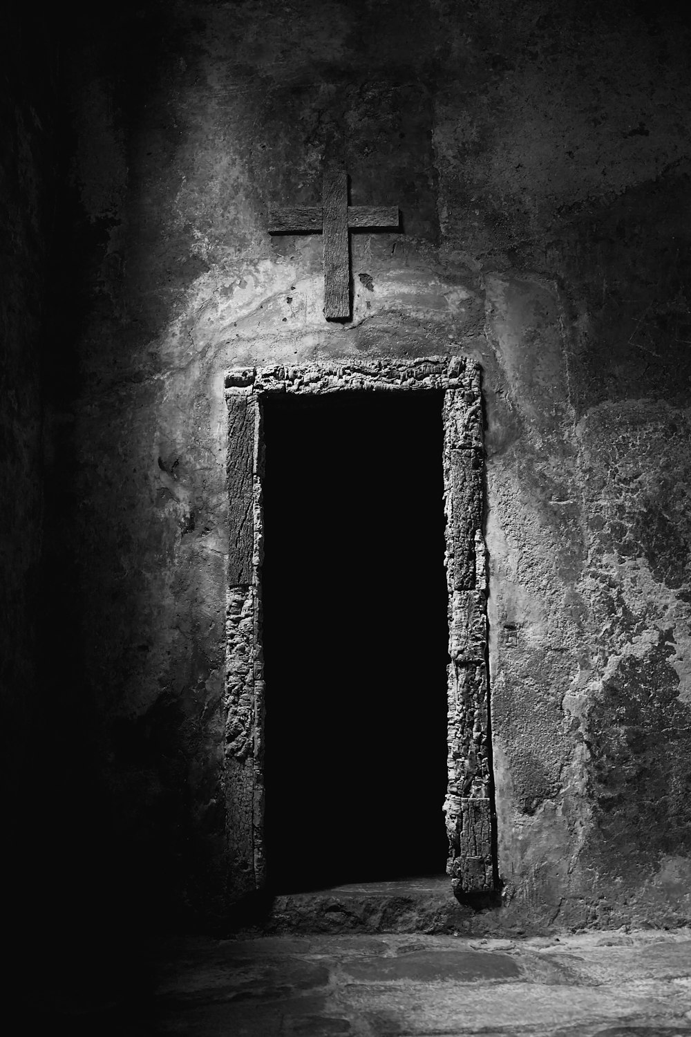 a black and white photo of a door and a cross