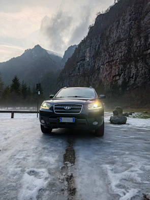 Close-up of a sleek black SUV with snow-capped mountains in the background