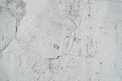 A textured cement wall with rough surfaces and subtle cracks. The surface has visible patterns and imperfections that create an uneven appearance.