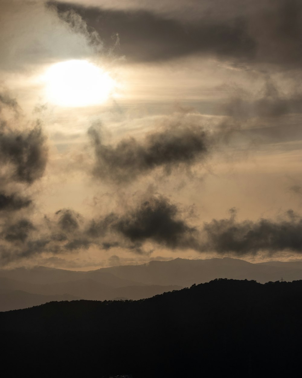 the sun is shining through the clouds over the mountains