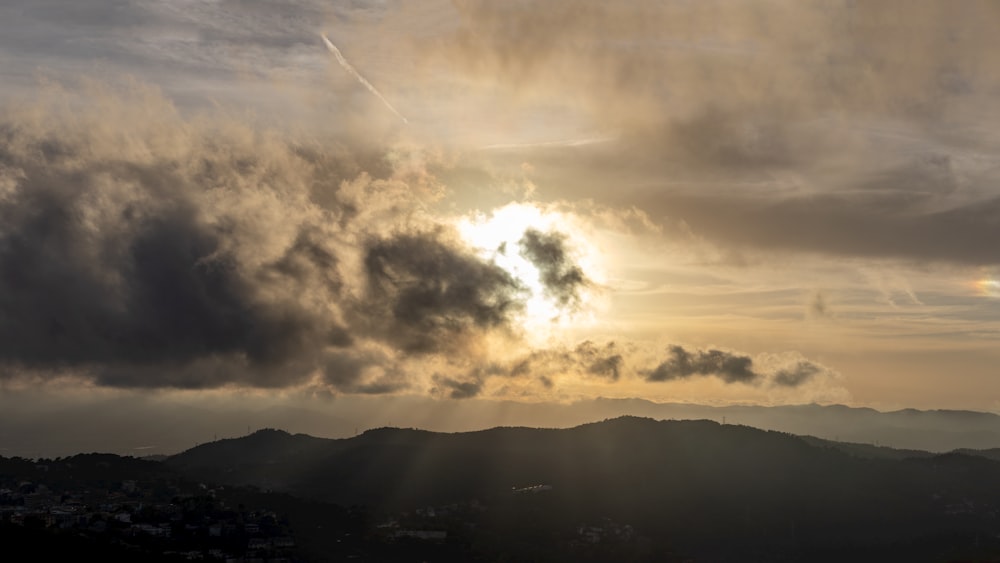 the sun is shining through the clouds over the mountains