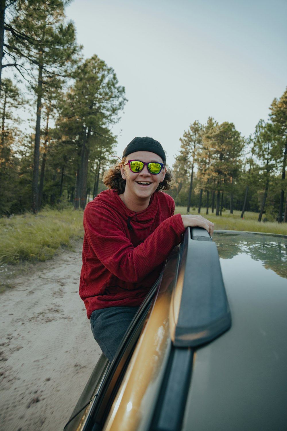 a woman wearing sunglasses leaning on the hood of a car