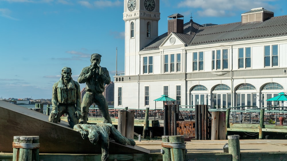 a statue of two men on a dock in front of a building