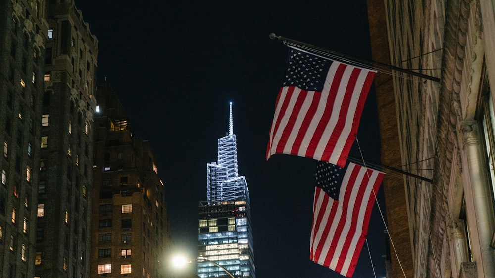 two american flags hanging from the side of a building