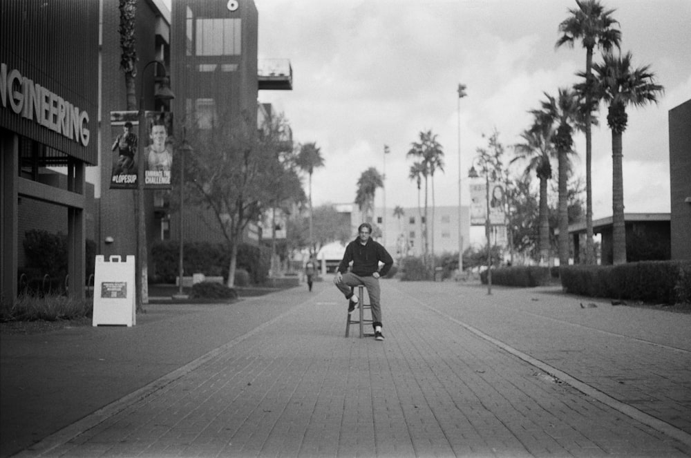 a black and white photo of a man sitting on a stool