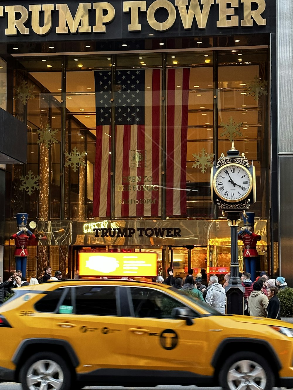 a yellow taxi driving past a trump tower building