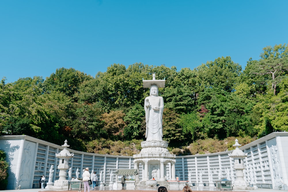 a statue of a person with a cross in the middle of a park