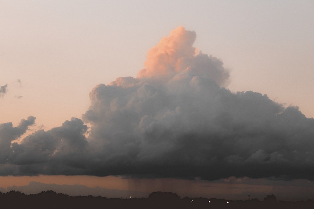 a large cloud is in the sky above a field