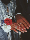 A close-up of hands adorned with mehendi, holding flower petals.