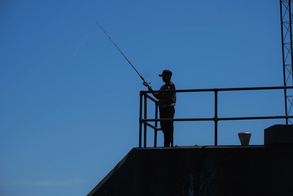 a man standing on top of a roof while holding a fishing rod