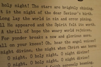Typed text on a textured paper background featuring lines from the Christmas carol 'O Holy Night'. The text appears to be typed with an old-fashioned typewriter font, and the paper has a warm, sepia tone.