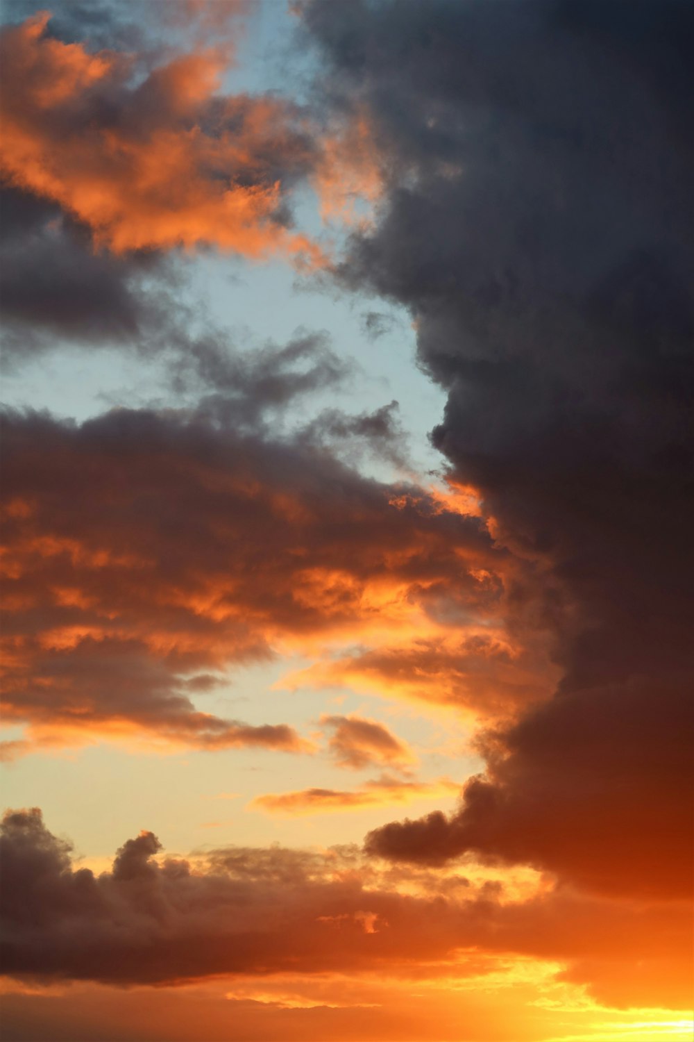 a plane flying through a cloudy sky at sunset