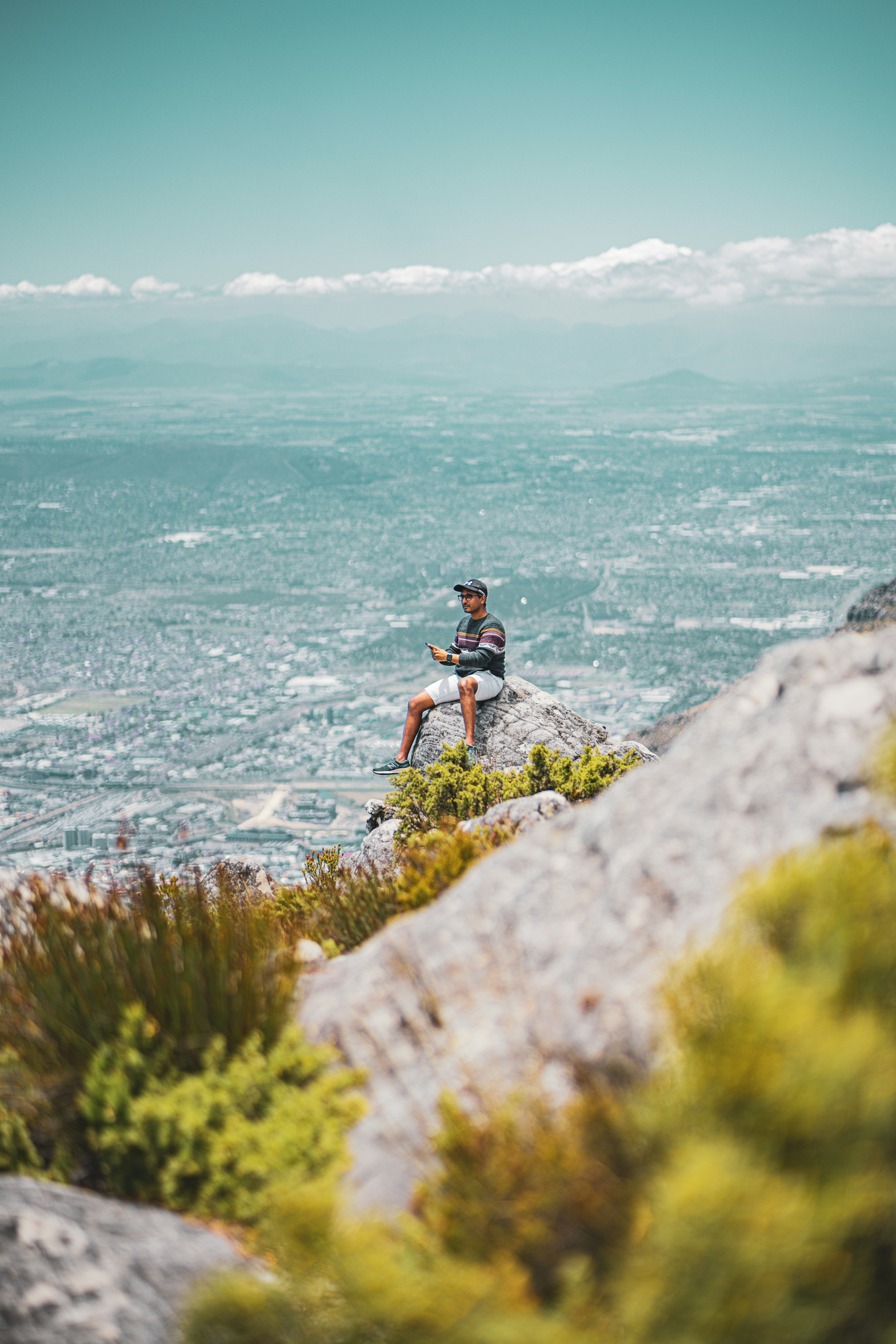 a man sitting on top of a rock next to the ocean