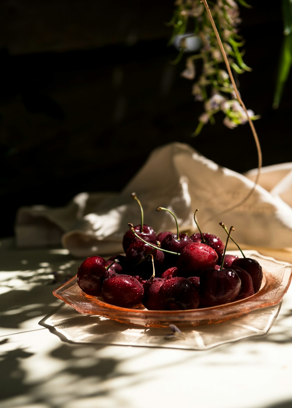 a glass bowl filled with cherries on top of a table