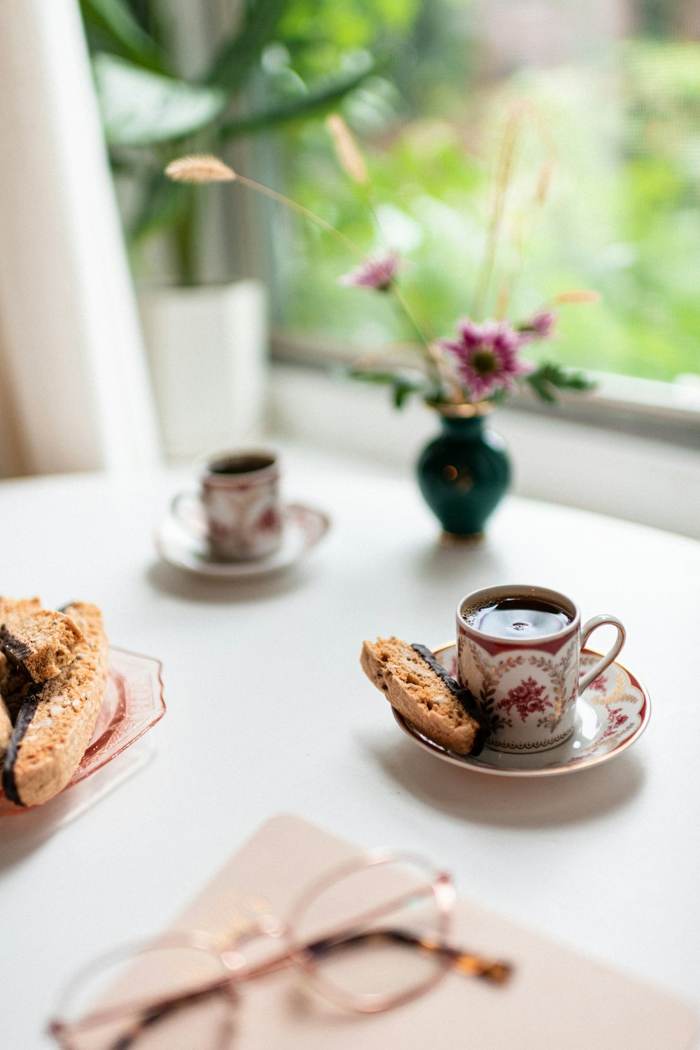 a white table topped with a cup of coffee and a plate of cookies