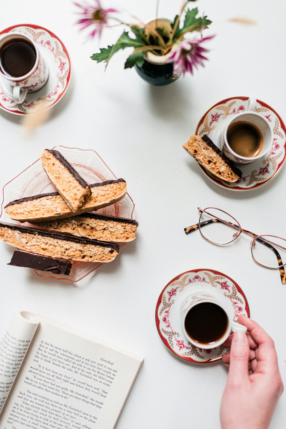 a person is holding a cup of coffee and some cookies