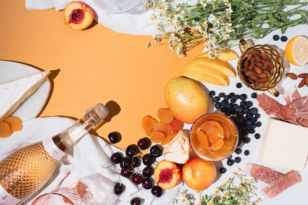 a table topped with fruit and cheese next to a bottle of wine